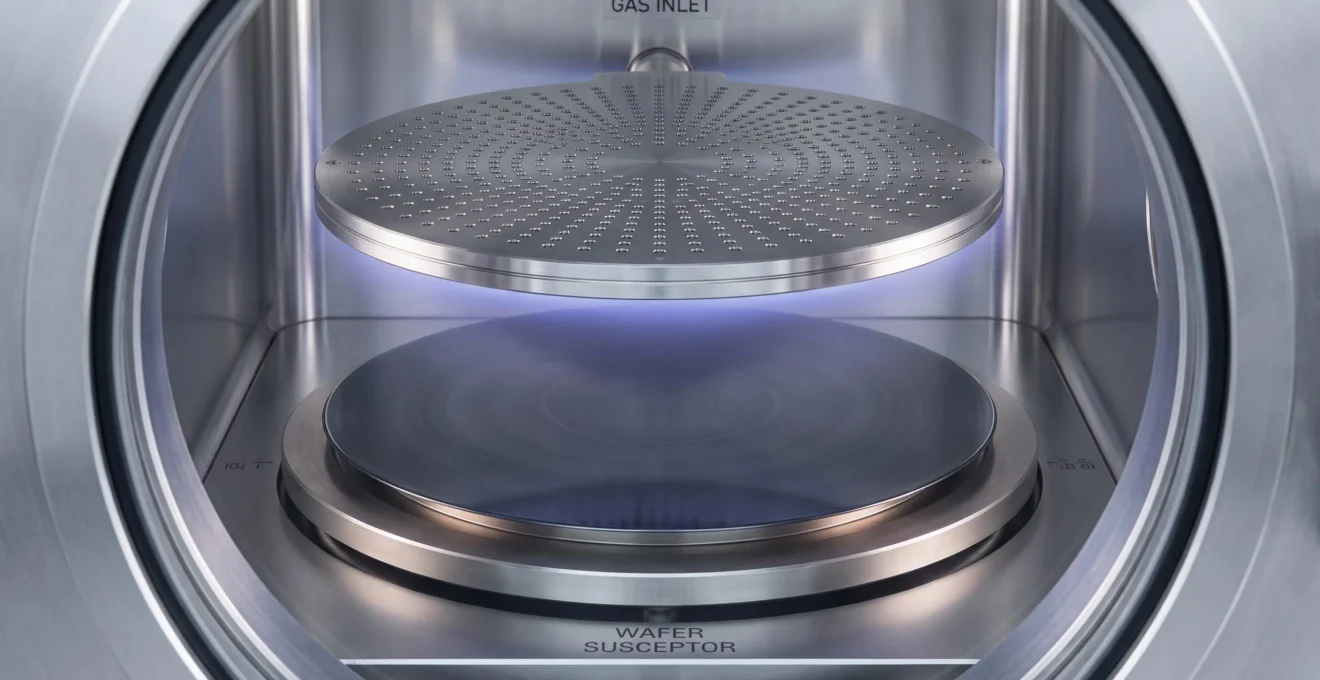 Silicon wafer positioned on heated pedestal inside chemical vapour deposition chamber with gas distribution showerhead visible above in precision processing environment